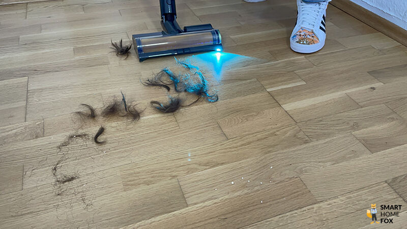 Die Dreame Z40 Station saugt Tierhaare auf einem Holzfußboden mit Hilfe der Laser-Schmutzerkennung. tierhaare, saugleistung, multi oberflächenbürste